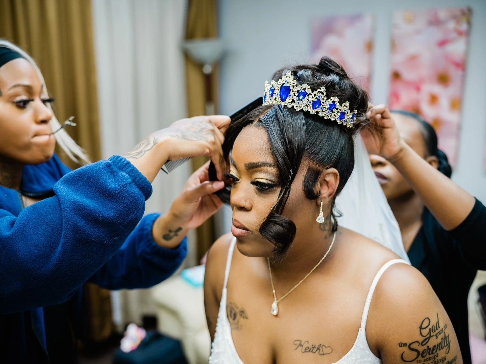 A sapphire tiara being set into a bride's finished updo while her veil is pinned behind her